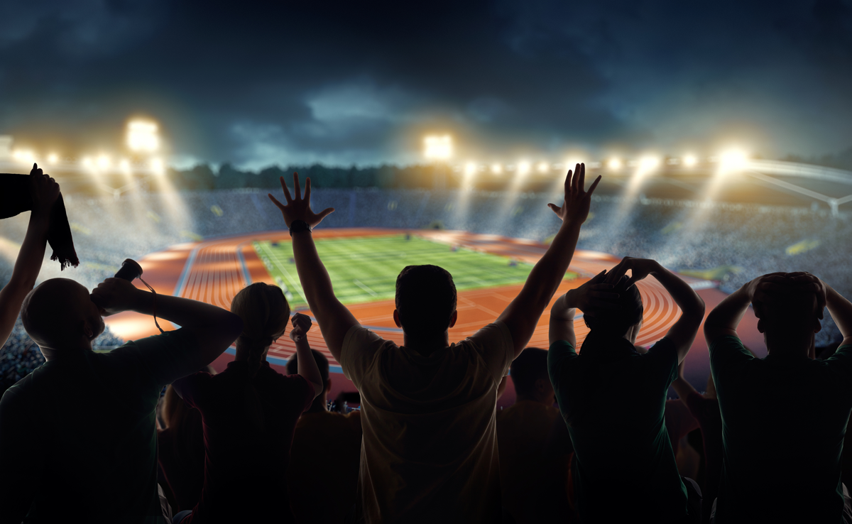 Crowd watching a brightly lit stadium at night